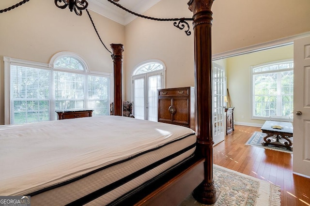 bedroom with light hardwood / wood-style floors, french doors, crown molding, and multiple windows