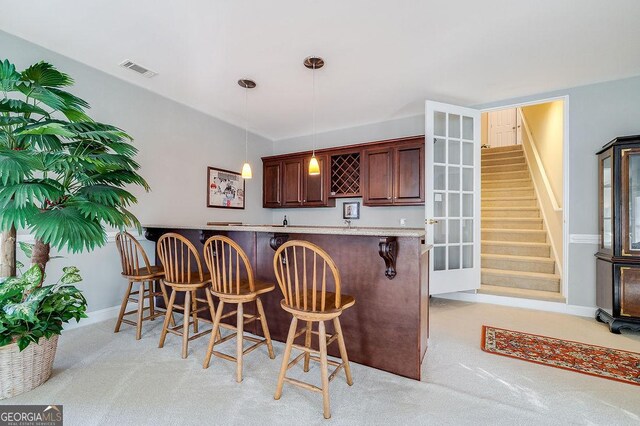 kitchen with decorative light fixtures, kitchen peninsula, a breakfast bar area, and light carpet