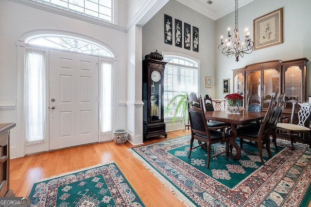 dining room with hardwood / wood-style flooring, a towering ceiling, and an inviting chandelier