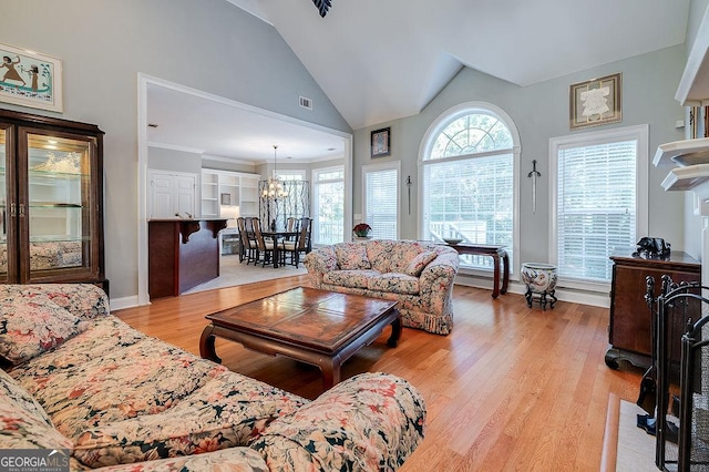 living room with an inviting chandelier, lofted ceiling, and light wood-type flooring