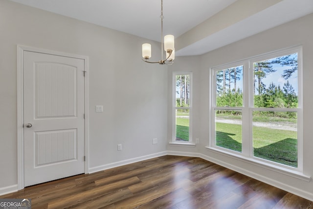 unfurnished dining area with a notable chandelier and dark wood-type flooring