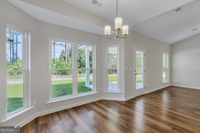 unfurnished dining area with a healthy amount of sunlight, an inviting chandelier, and dark wood-type flooring