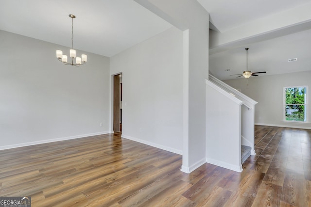 spare room featuring ceiling fan with notable chandelier and dark wood-type flooring