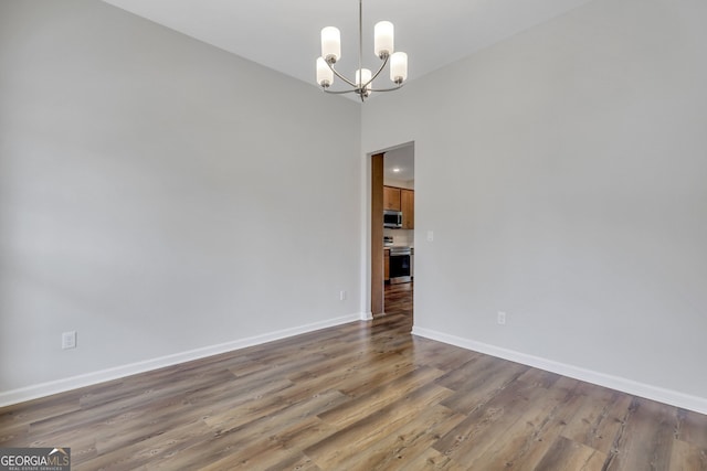 unfurnished room with a chandelier and hardwood / wood-style floors