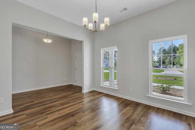 unfurnished room with an inviting chandelier and dark wood-type flooring