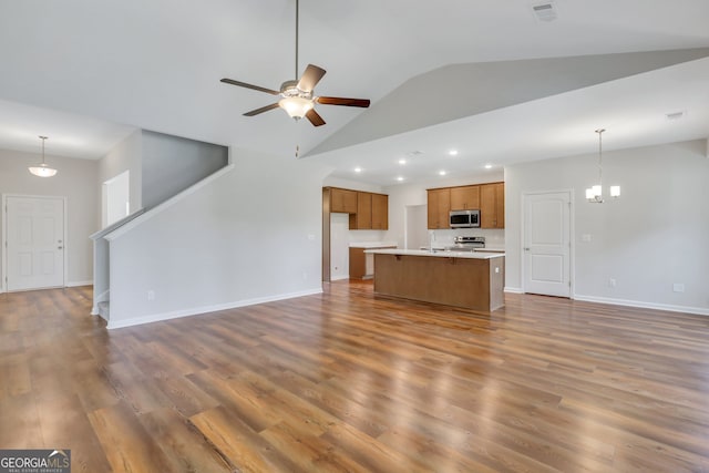 unfurnished living room with ceiling fan with notable chandelier, high vaulted ceiling, dark hardwood / wood-style floors, and sink