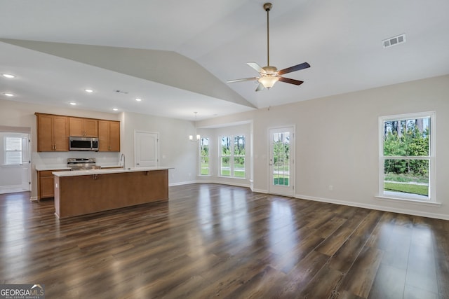 kitchen with lofted ceiling, a kitchen island with sink, stainless steel appliances, ceiling fan with notable chandelier, and dark hardwood / wood-style flooring