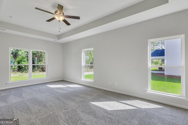 carpeted spare room with a raised ceiling and ceiling fan