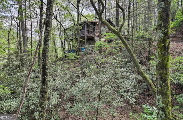 back of property with a balcony and a wooded view