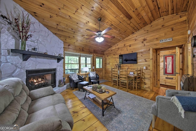 living area with wooden walls, lofted ceiling, hardwood / wood-style flooring, wood ceiling, and a fireplace