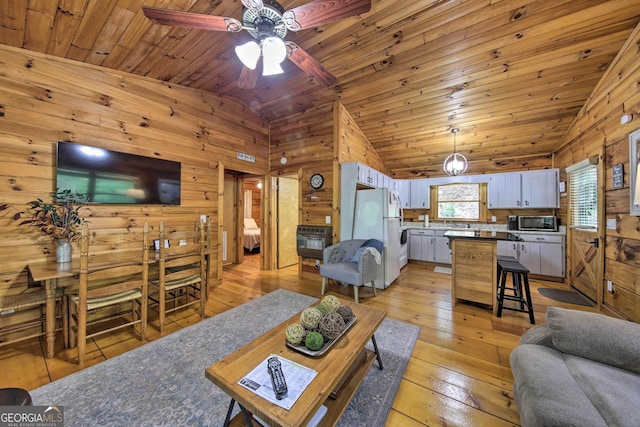 living area with lofted ceiling, wood walls, light wood-style flooring, and wood ceiling