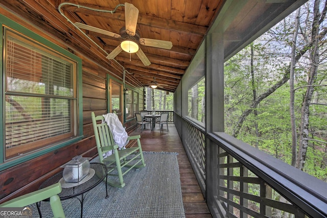 unfurnished sunroom with vaulted ceiling, wood ceiling, and a ceiling fan