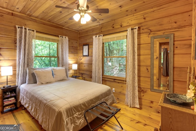 bedroom featuring wooden ceiling, wood walls, and light wood finished floors