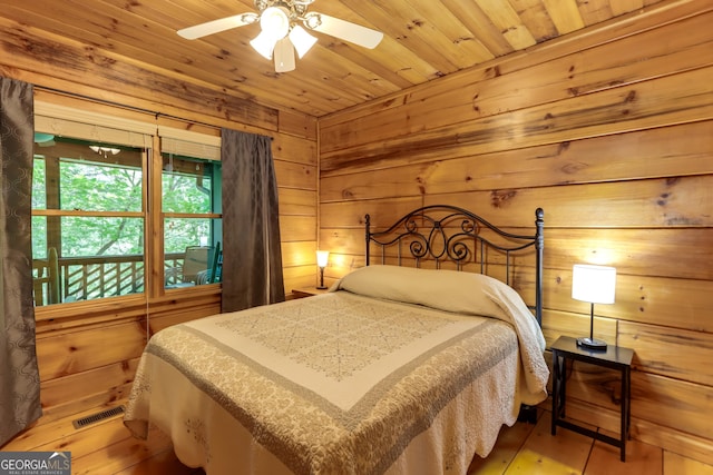 bedroom featuring wooden ceiling, wooden walls, visible vents, and wood finished floors