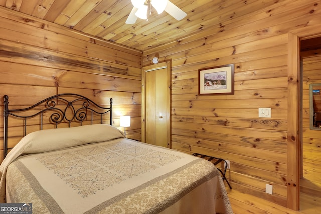 bedroom with a closet, wooden ceiling, wood walls, and a ceiling fan