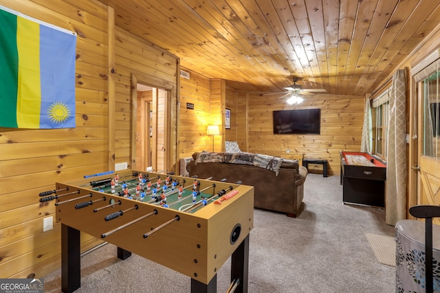 recreation room featuring carpet, wooden ceiling, ceiling fan, and wood walls