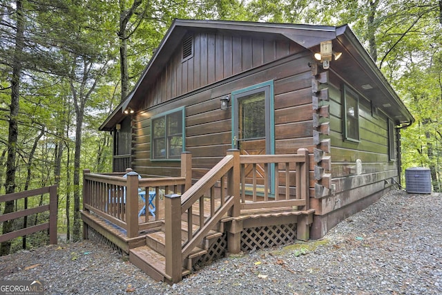 rear view of property featuring board and batten siding, central AC, fence, and log exterior