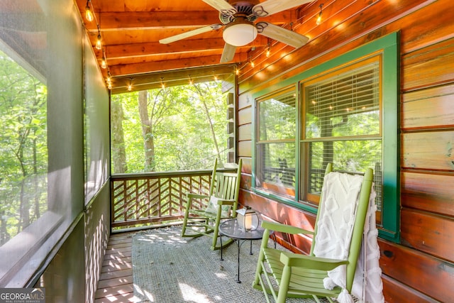 unfurnished sunroom featuring a ceiling fan and beam ceiling