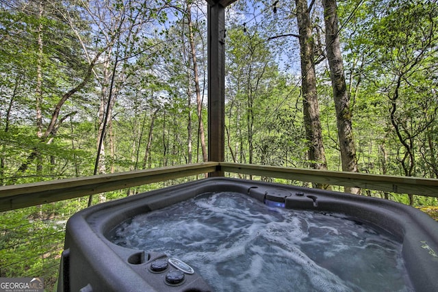 deck featuring a hot tub and a view of trees