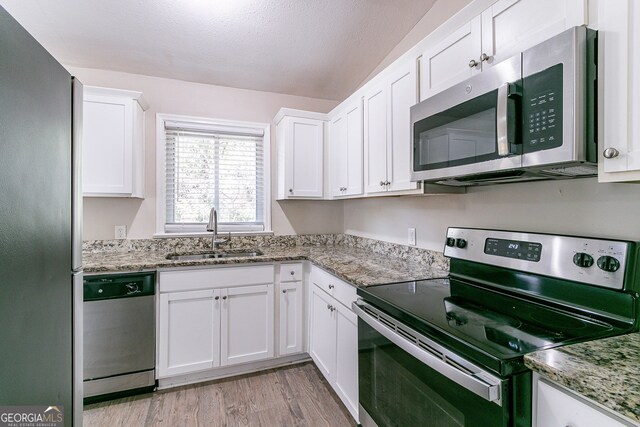 1278 Lynwyn Ln SE, Atlanta, GA 30316 - kitchen featuring light stone counters, light wood finished floors, a sink, stainless steel appliances, and white cabinetry