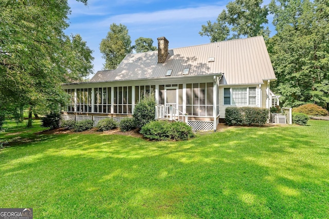 rear view of property featuring a sunroom, a yard, and central air condition unit