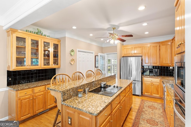 kitchen with ceiling fan, appliances with stainless steel finishes, a center island, a breakfast bar area, and decorative backsplash