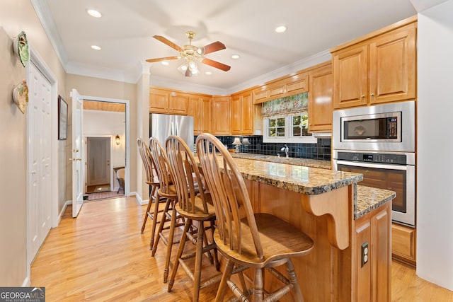 kitchen with light hardwood / wood-style floors, ceiling fan, and stainless steel appliances