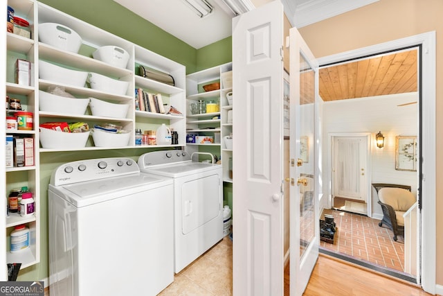 clothes washing area with light wood-type flooring, washer and clothes dryer, and crown molding