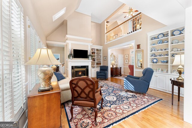 living room with light wood-type flooring, ceiling fan, and high vaulted ceiling