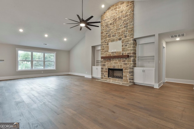 unfurnished living room featuring high vaulted ceiling, dark hardwood / wood-style flooring, a stone fireplace, and ceiling fan