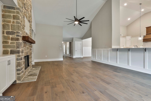 unfurnished living room featuring high vaulted ceiling, dark hardwood / wood-style flooring, ceiling fan, and a fireplace