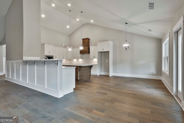 kitchen with dark wood-type flooring, white cabinets, a breakfast bar area, high vaulted ceiling, and pendant lighting