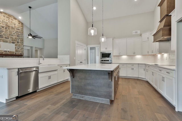 kitchen with white cabinetry, appliances with stainless steel finishes, dark hardwood / wood-style floors, high vaulted ceiling, and a center island