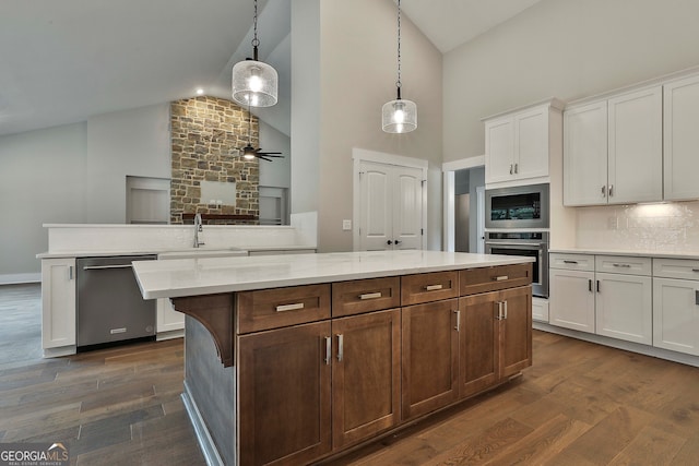 kitchen with dark wood-type flooring, white cabinetry, decorative light fixtures, and stainless steel appliances