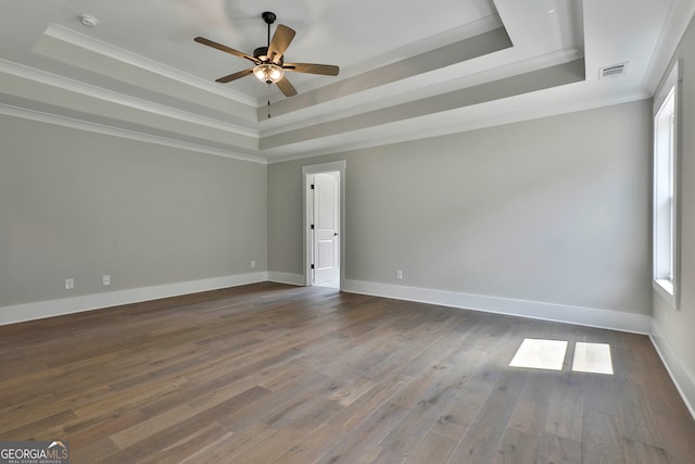 spare room with ornamental molding, dark wood-type flooring, ceiling fan, and a tray ceiling