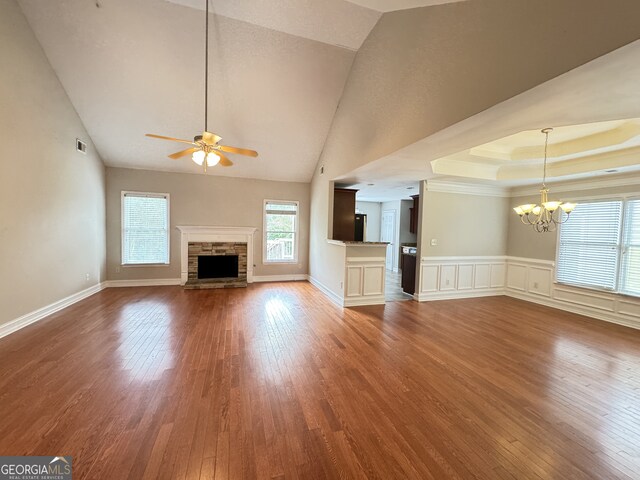 unfurnished living room featuring ceiling fan with notable chandelier, a fireplace, hardwood / wood-style floors, and high vaulted ceiling