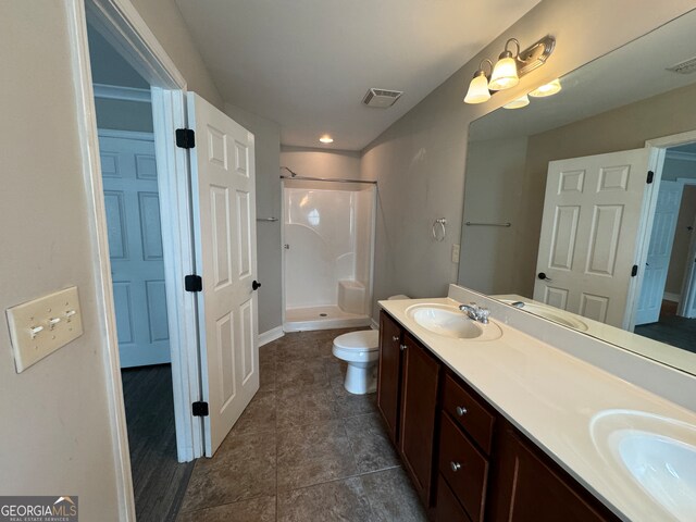 bathroom with a shower, vanity, toilet, and tile patterned floors