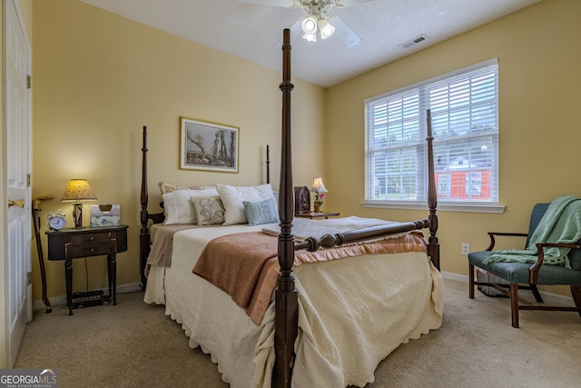 carpeted bedroom featuring ceiling fan and a textured ceiling