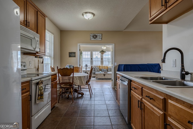 kitchen featuring white appliances, sink, dark tile patterned flooring, and plenty of natural light