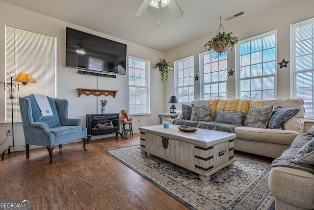 living room with a textured ceiling, dark hardwood / wood-style floors, and ceiling fan