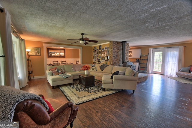 living room with wood-type flooring, a textured ceiling, a wood stove, and ceiling fan