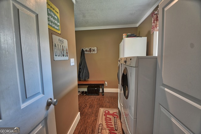 clothes washing area featuring a textured ceiling, cabinets, dark hardwood / wood-style floors, independent washer and dryer, and crown molding