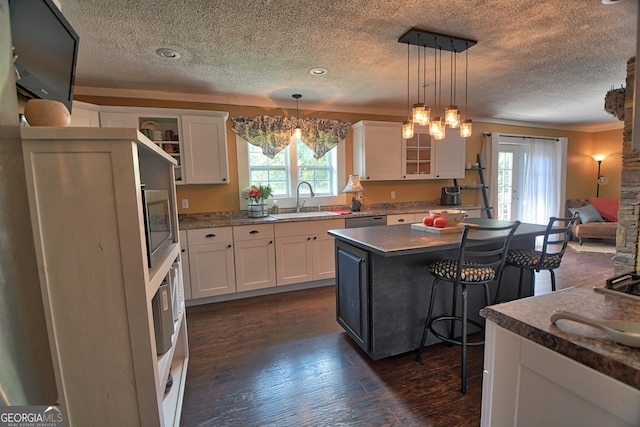 kitchen with a kitchen breakfast bar, dark wood-type flooring, a center island, and a healthy amount of sunlight