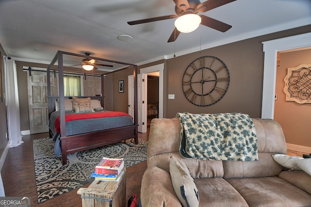 bedroom with a barn door, crown molding, hardwood / wood-style floors, and ceiling fan