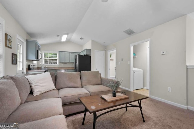 carpeted living room with lofted ceiling and washer / dryer