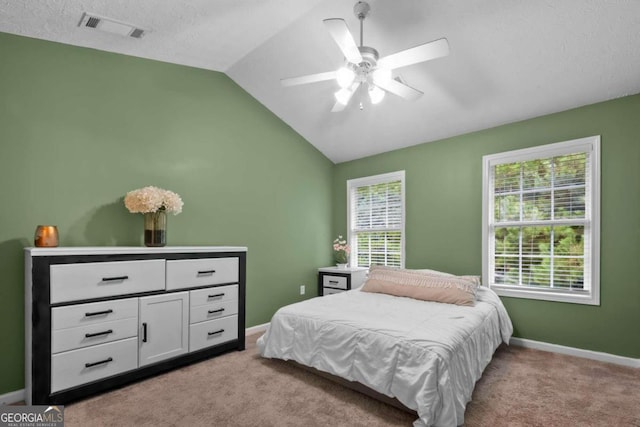 carpeted bedroom featuring multiple windows, a textured ceiling, vaulted ceiling, and ceiling fan