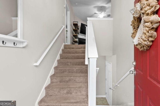 staircase featuring ceiling fan