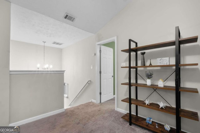 hallway with vaulted ceiling, an inviting chandelier, and light colored carpet