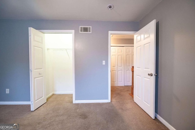 unfurnished bedroom featuring light carpet and a closet