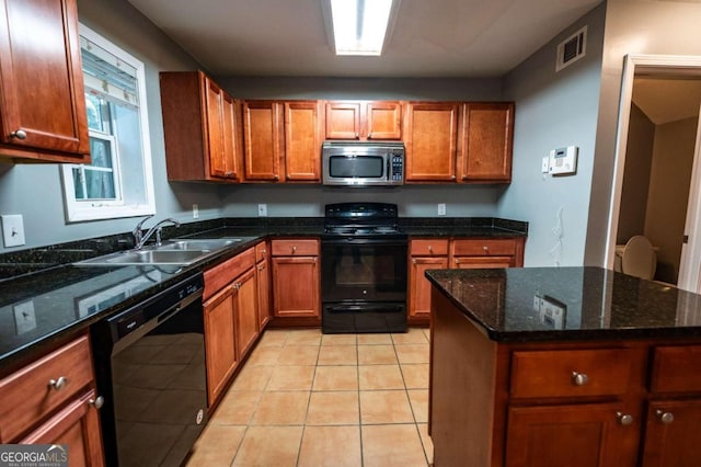 kitchen with dark stone counters, black appliances, light tile patterned floors, and sink